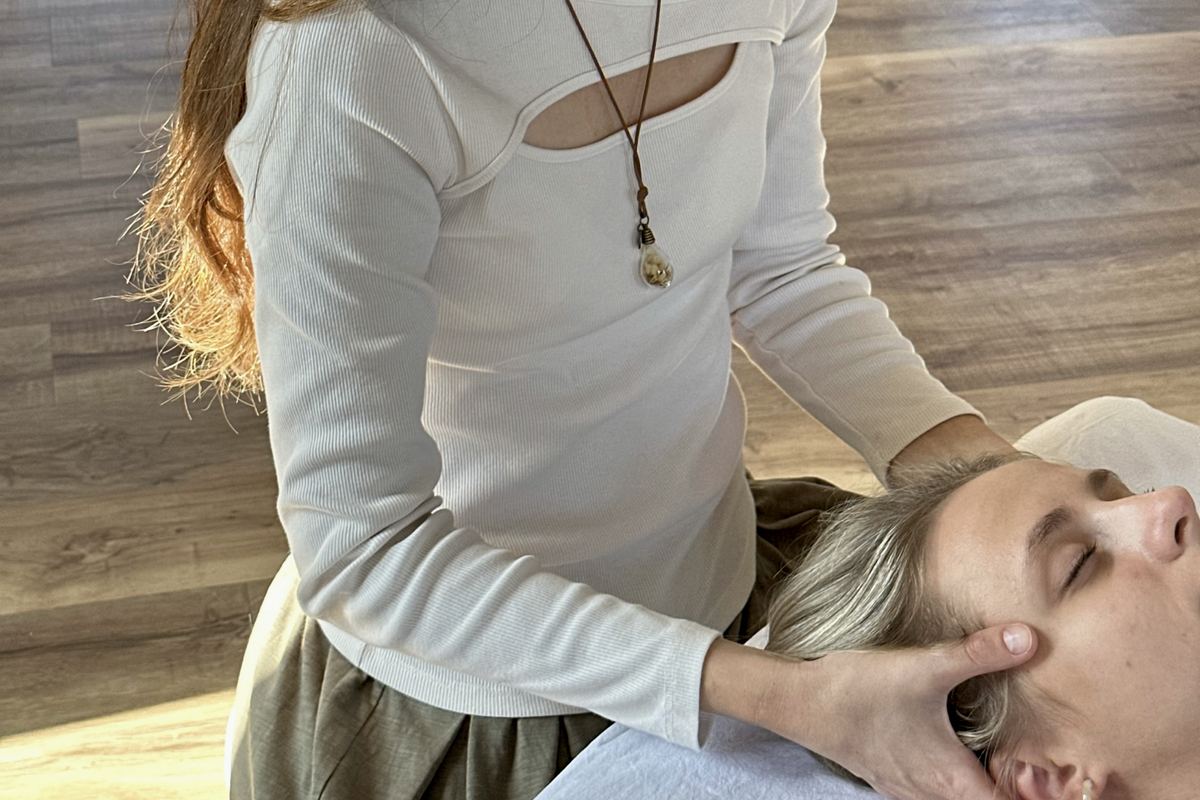 Kira holding a client’s head in a light, quiet room