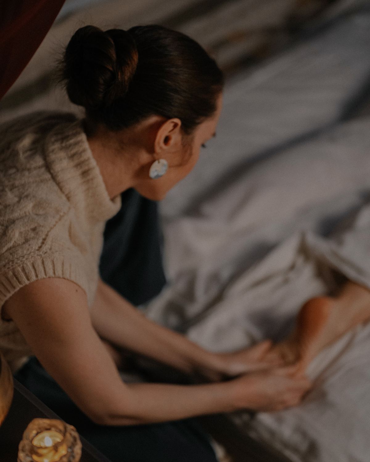 Kira working with a client on the massage table in warm candlelight
